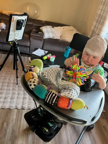 Charlie, an infant with epilepsy, plays with toys while wearing bandages from surgery.