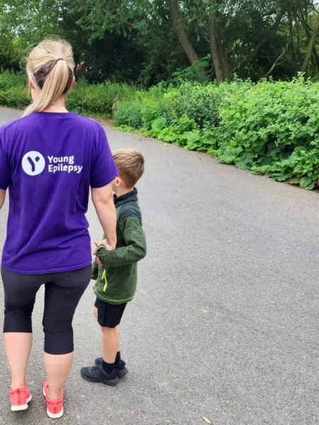 A mum wears a Young Epilepsy t-shirt while walking with her two sons.