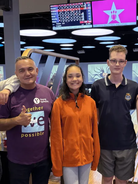 A group of young people and Young Epilepsy staff smile at a bowling alley.