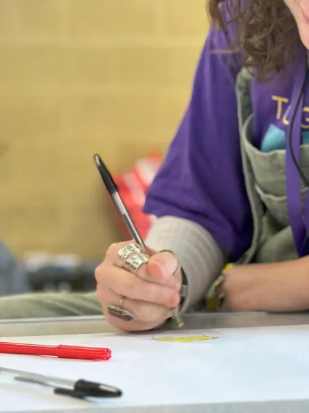 Young girl wearing a Purple Day t-shirt writing in a classroom