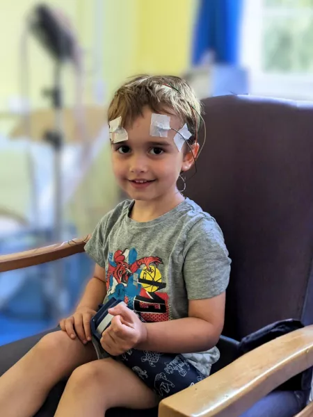 A young boy sits in a doctors office wearing an EEG.