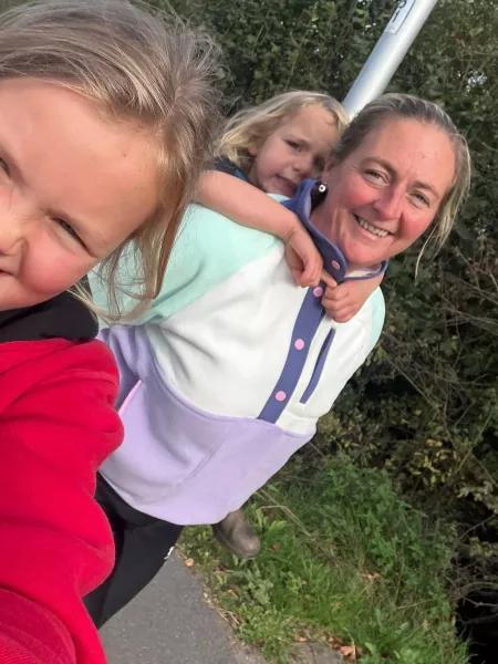 A woman and her two children smile in a selfie outdoors.