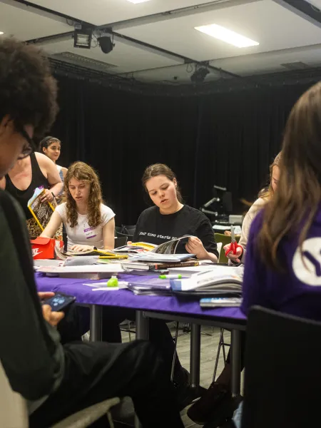 A group of young people make make collages at a table in Young Epilepsy clothing.