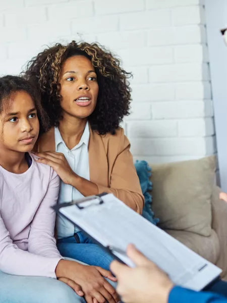 A doctor speaks to a mother and daughter about his notes.
