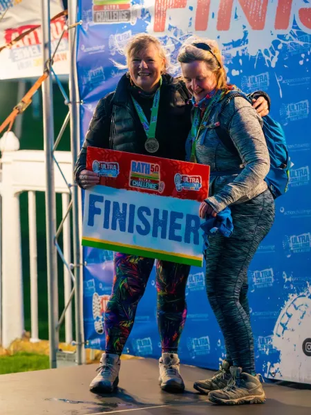 2 event participants  posing with a finisher sign