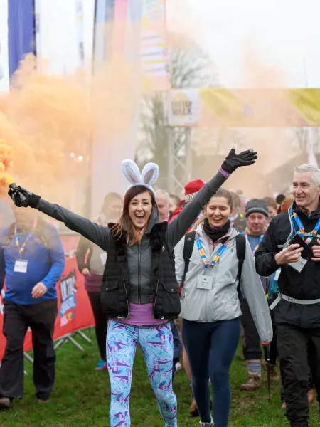 Walkers through a start archway with coloured smoke 