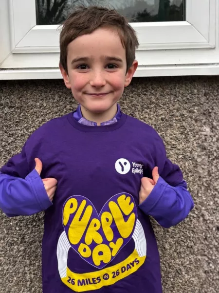 Young boy smiles with thumbs up wearing a 26 miles for 26 days for purple day t-shirt