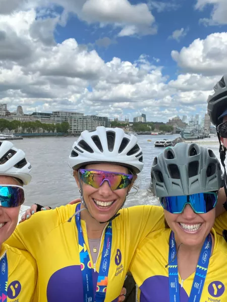 Four cyclist in helmets smile in from of a seascape.