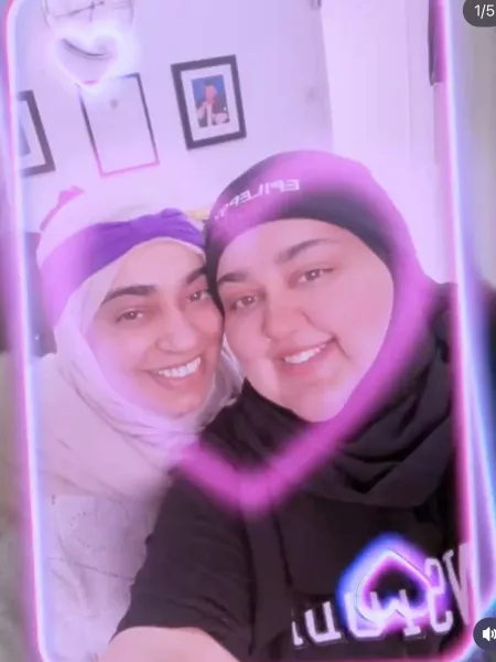 Two women in headscarves smile in a selfie.