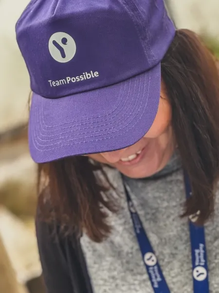 A woman poses in a Young Epilepsy #TeamPossible purple cap