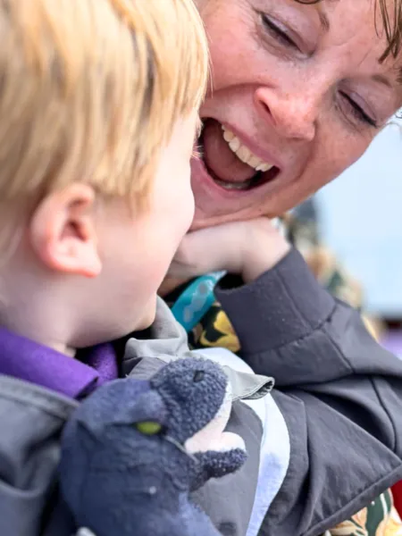 A mother smiles while holding her son.