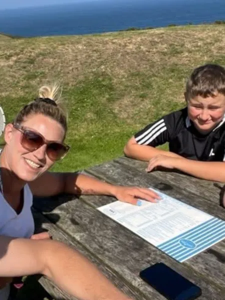 A family sit at a bench by the ocean.