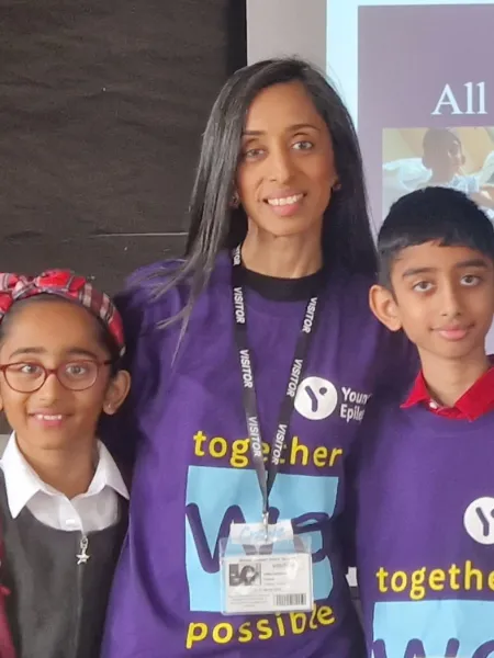 A mother and her two children stand in front of a children's assembly on epilepsy.