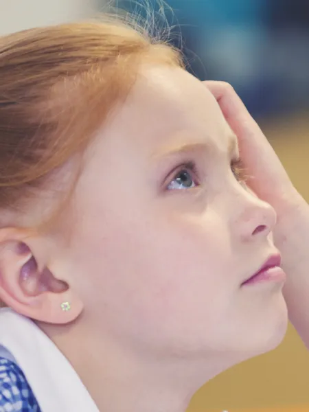 A school child looks up thoughtfully.