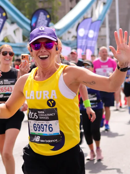 London Marathon Runner smiles and waves with a purple cap