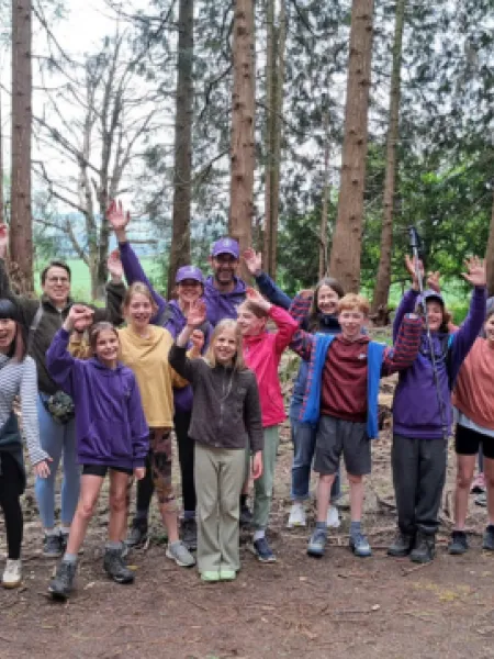 A group of hikers celebrate in a forest.