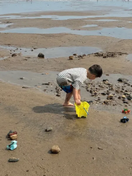 A young boy plays with a bucket on a beach.