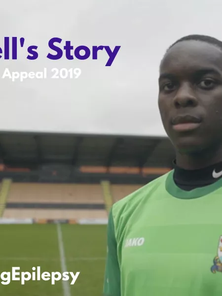 Renell, a young man in a green football shirt, poses for the #FacingEpilepsy campaign, titled 'Renell's Story'.