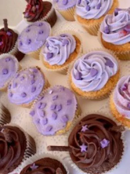 Brown and purple cupcakes sit on a white square dish as part of a sale for Purple Day 2022.