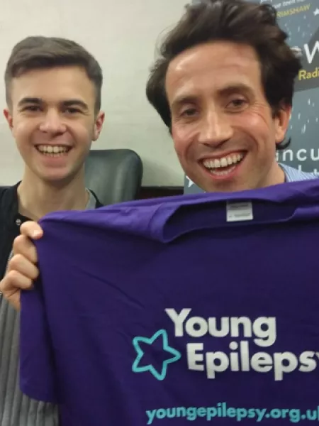 Broadcaster and author Nick Grimshaw and young man Lewis smile while holding up a Young Epilepsy t-shirt.